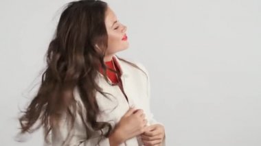 Çekici, rüya gibi esmer, kulaklıkla müzik dinleyen, gri arka planda başını sallayan ve dans eden kız.