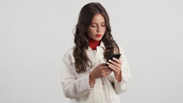 Привлекательная Брюнетка Мобильным Телефоном Счастливо Машет Рукой Приветствуя Камере Сером — стоковое видео