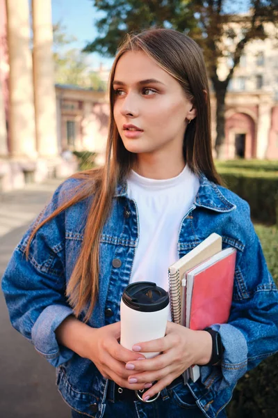 Kot ceketli, şık, genç, çekici bir kız. Düşünceli bir şekilde dışarı bakıyor.