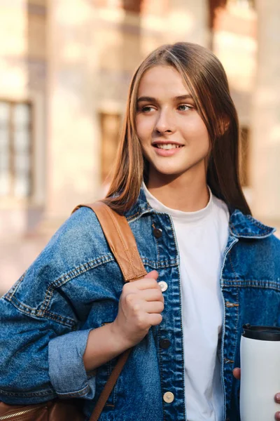 Ung attraktiv casual student flicka i denim jacka glatt tittar bort i universitetet utomhus — Stockfoto