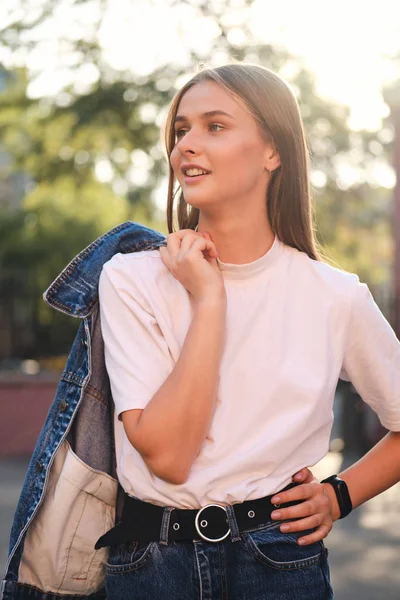 Menina casual elegante atraente com jaqueta de ganga no ombro sonhadoramente olhando para o exterior — Fotografia de Stock