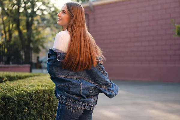 Ganska bekymmerslös avslappnad brun hår flicka i denim jacka glatt tittar bort utomhus — Stockfoto