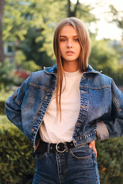 Attraente grave ragazza dai capelli castani casual in giacca di jeans sensualmente alla ricerca in macchina fotografica all'aperto — Foto Stock