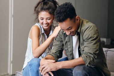 Genç, çekici, çok uluslu, sıradan bir çift evde mutlu bir şekilde gülüyor.