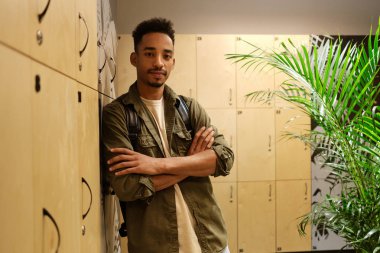 Genç ve yakışıklı Afro-Amerikan adam el ele tutuşup soyunma odasındaki kameraya bakıyor.