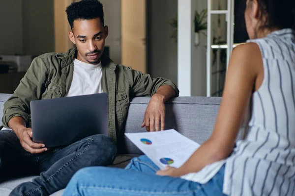 Jovem homem afro-americano casual bonito com laptop trabalhando com colega em novo projeto no espaço de co-trabalho moderno — Fotografia de Stock