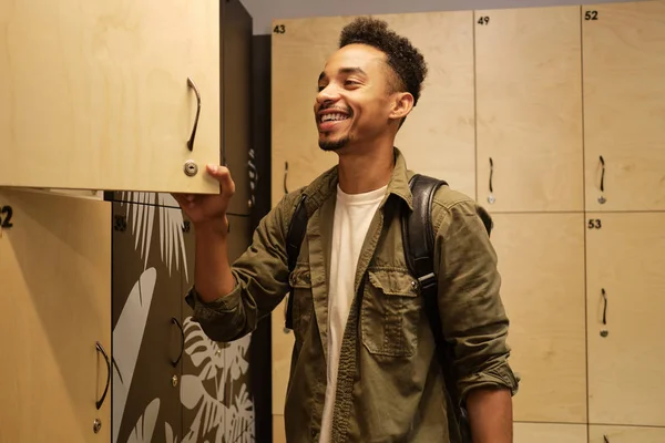 Genç ve çekici Afro-Amerikan bir adam ofis vestiyerindeki dolabı mutlulukla açıyor. — Stok fotoğraf