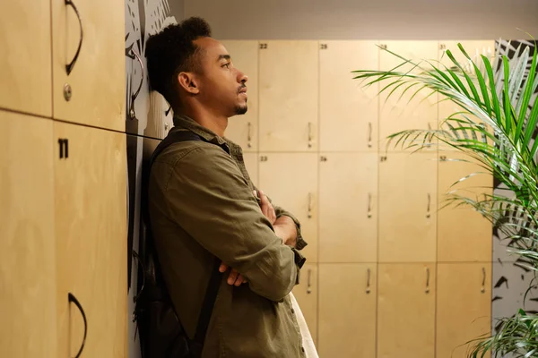 Sidovy över ung vacker avslappnad afroamerikansk man tankeväckande står i omklädningsrummet — Stockfoto