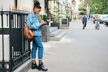 Sırt çantası ve not defteriyle şehir caddesinde özenle ders çalışan sıradan bir Afro-Amerikan öğrenci görüntüsü.