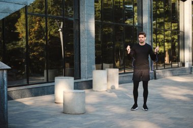 Genç, çekici, kendine güveni tam bir sporcu. Şehir caddesinde idman yaparken ip atlıyor.