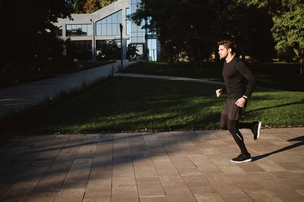 아침에 잘 생긴 젊은 스포츠 선수가 시립 공원에서 뛰고 있습니다 — 스톡 사진