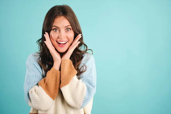 Gadis cantik yang lucu dengan sweater yang nyaman dengan penuh semangat melihat ke kamera di atas latar belakang biru — Stok Foto