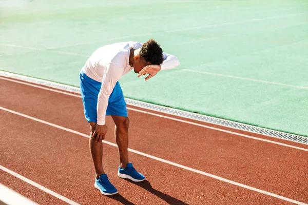 피로에 지친 젊은 아프리카 계 미국인 운동 선수 가 시 경기장에서 경주 트랙을 달리는 중에 멈추었다 — 스톡 사진