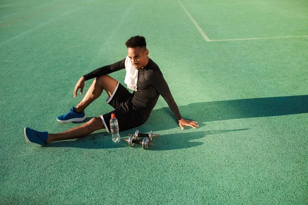 젊고 잘생긴 아프리카 계 미국인 운동 선수 가 운동장에서 쓰레기 벨을 가지고 운동을 한 후에 쉬고 있다 — 스톡 사진