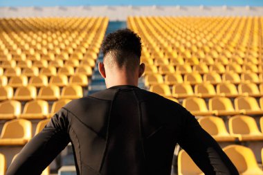 Genç ve güçlü Afrikalı Amerikalı sporcunun boş stadyum koltukları arasındaki arka görüntüsü 