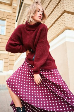 Şık, sarışın, örgü süveter giyen, rüyasında sokakta poz veren bir kızın kavramsal fotoğrafı.