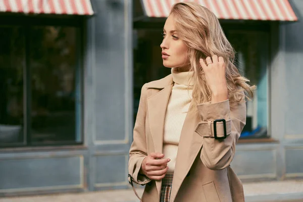 Side view of beautiful pensive blond girl in trench coat thoughtfully looking away on street — Stock Photo, Image