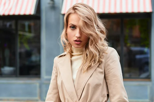 Attraktiv sexig blond tjej i snygg trenchcoat sensuellt tittar i kameran på stadens gata — Stockfoto