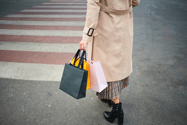 Закрыть стильную женщину с сумками для покупок, идущую по пешеходному переходу
 