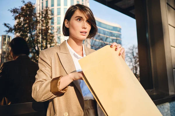 Giovane attraente donna d'affari elegante eccitatamente aprendo la busta che lavora con documenti su strada — Foto Stock