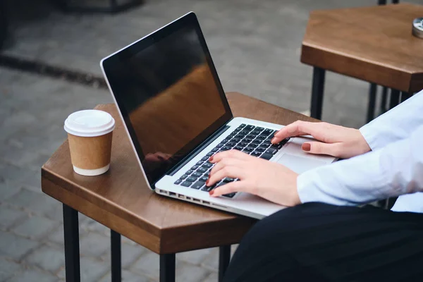 Close up elegante empresária com café para ir trabalhar no laptop no café na rua — Fotografia de Stock