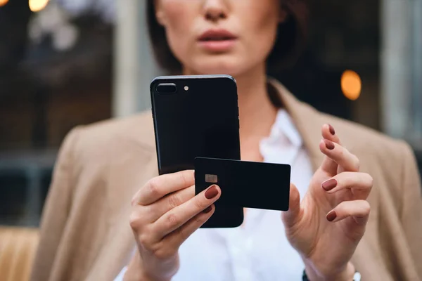 Primer plano elegante mujer de negocios con tarjeta de crédito utilizando el teléfono celular al aire libre — Foto de Stock