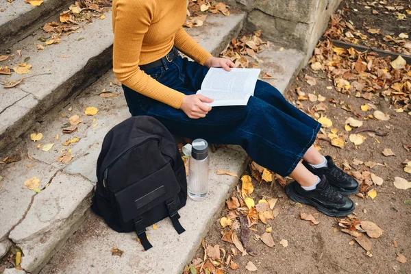 Zblízka ležérní studentská dívka čtení knihy na schodech v parku — Stock fotografie