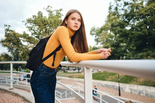 Bella studentessa casual con zaino intensamente guardando lontano nel parco della città — Foto Stock