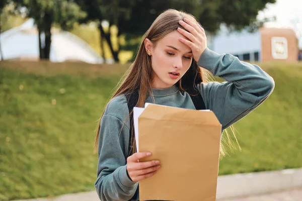 Sconvolto ragazza studente casuale purtroppo apertura busta con i risultati degli esami nel parco della città — Foto Stock