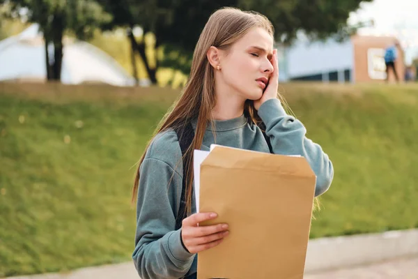 Frustrante ragazza studente casuale purtroppo apertura busta con i risultati degli esami nel parco della città — Foto Stock