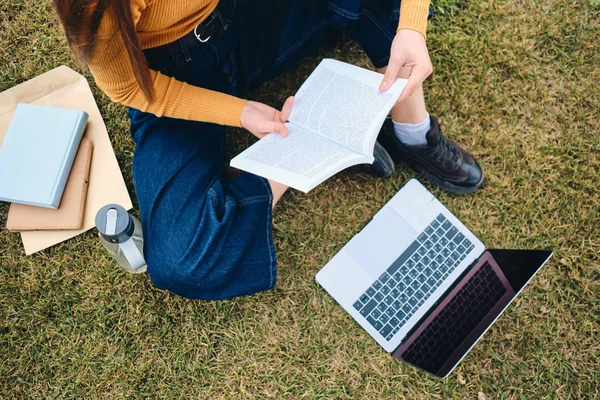 Zblízka ležérní student dívka studuje s notebookem a rezervovat na trávníku v parku — Stock fotografie