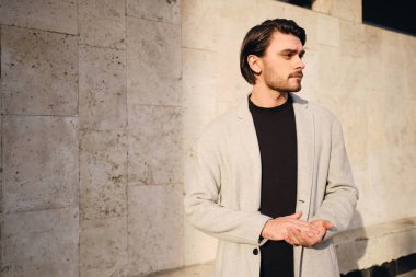 Palto giymiş yakışıklı bir adamın düşünceli bir şekilde dışarı bakışları.