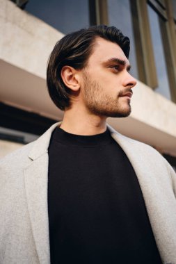 Çekici, sıradan, ceketli, esmer adamın yan görünüşü. Düşünceli bir şekilde dışarı bakıyor.