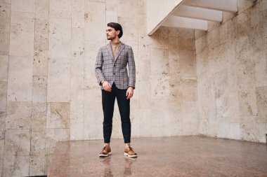 Kareli ceketli yakışıklı adam dikkatle dışarı bakıyor.