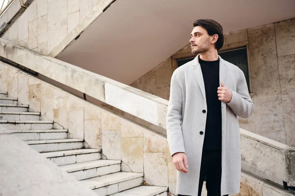 Jovem atraente homem elegante no casaco pensativo olhando para longe na rua — Fotografia de Stock