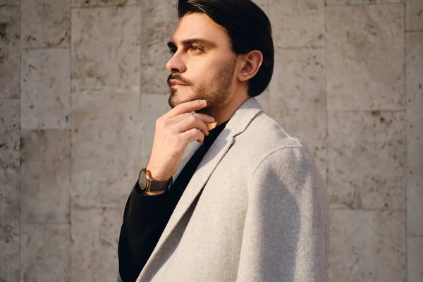 Side view of young handsome stylish man in coat thoughtfully looking away outdoor — Stock Photo, Image