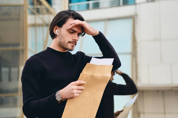 Молода сумна брюнетка людина вдумливо читає конверт з відповіддю на відкритий — стокове фото