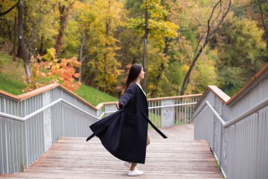Young beautiful casual woman dreamily walking in autumn park