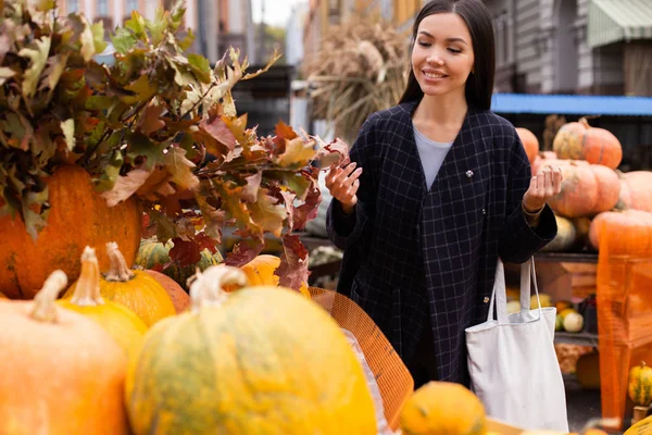 Jonge aantrekkelijke glimlach casual vrouw op boerderij winkel gelukkig op zoek naar pompoen voor Halloween dag buiten — Stockfoto