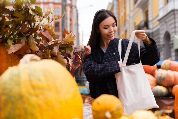 Jonge aantrekkelijke casual vrouw gelukkig kopen pompoen in de herfst boerderij winkel buiten — Stockfoto
