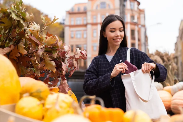 Retrato de jovem sorrindo mulher casual feliz à procura de bolsa no saco na loja fazenda outono ao ar livre — Fotografia de Stock