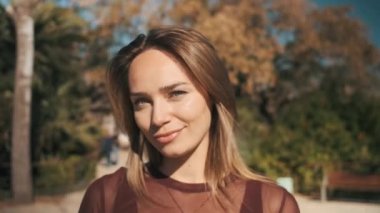 Güzel bir parkta elinde akıllı telefonla kameraya poz veren güzel, gülümseyen bir kızın fotoğrafını çekiyorum. Çekici sarışın kız utangaç ve kameralı telefona şehvetli bir şekilde bakıyor. Ara beni.