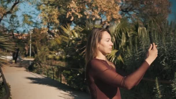 Śledzenie Ujęcia Atrakcyjnej Dziewczyny Pomocą Smartfona Aby Porozmawiać Rodziną Wideo — Wideo stockowe