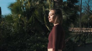 Mavi gözlü, güzel sarışın bir kızın görüntüsünü alıyorum. Plak rengi giyiyor. Üstü açık ve sinsi bir şekilde parktaki kameraya bakıyor.