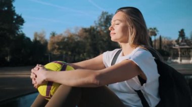 Futbol ellerinin arasında güzel bir futbolcunun fotoğrafını çekiyorum. Şehir parkında güneşin altında rüya gibi dinleniyor.