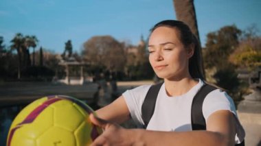 Futbol antrenmanından sonra hayali olarak güneşte dinlenen, elinde futbol olan güzel bir kızın portresi. Muhteşem futbol kızı.