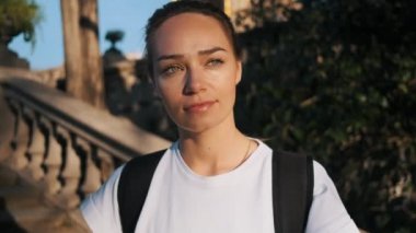 Sırt çantalı, elinde futbol topuyla oynayan çekici bir futbolcu kızın izini sürüp, dışarıda güneşin altında kendinden emin bir şekilde başka tarafa bakıyor. Motivasyonlu bayan futbolcu