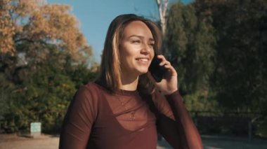 Güzel sarışın kız şehir parkında telefonda şehvetle konuşuyor.