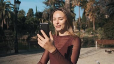 Şehir parkında yürürken güzel bir kızın görüntüsünü izlemek ve akıllı telefondan ailesiyle mutlu bir şekilde haberleşmek.