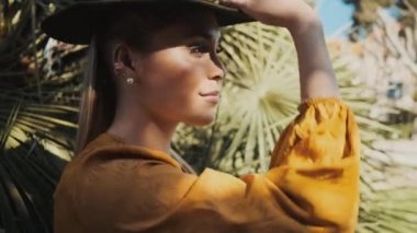 Şapka takan ve kendinden emin bir şekilde dışarı bakan güzel bir kadının yan görüntüsü.